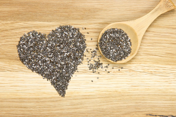 wooden spoon filled with black chia seeds and heart symbol